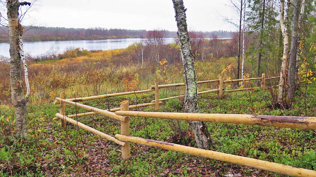 Etualalla aidattu alue. Taustalla syksyinen järvimaisema.