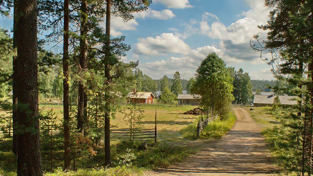 Hiekkatie johtaa männiköstä riukuaidan ympäröimän laitumen ohi vanhaan pihapiiriin. Pihapiirissä punainen päärakennus ja harmaita ulkorakennuksia. Sinisellä taivaalla poutapilviä.